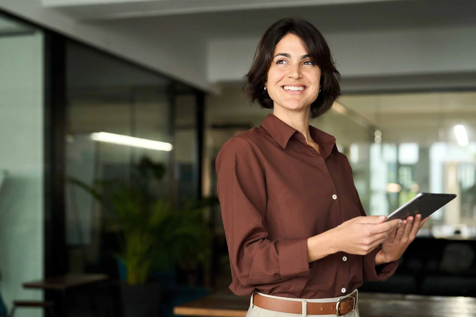 Profissional sorrindo com um tablet, em um ambiente de trabalho acolhedor